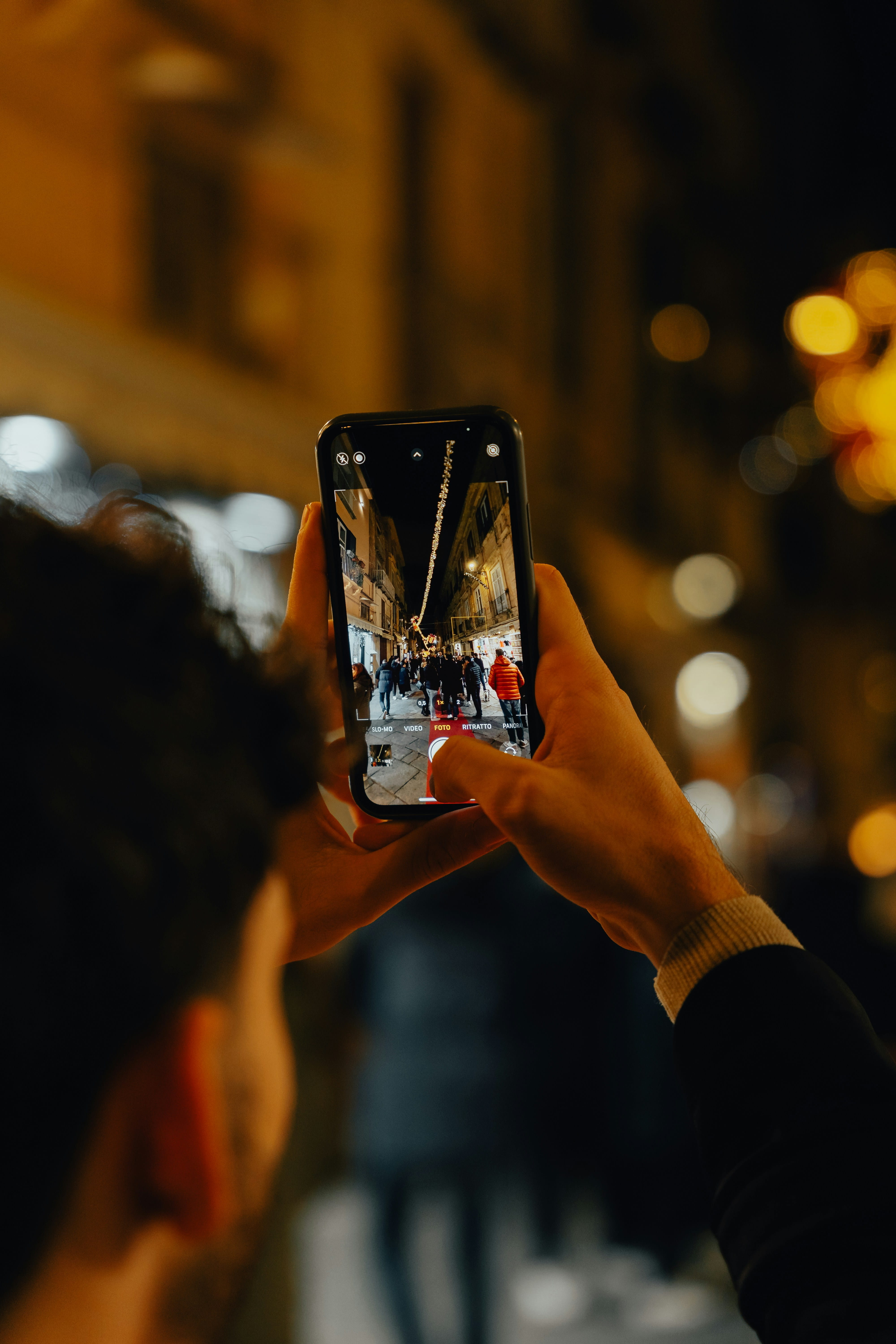 A person capturing a city street at night on their phone
