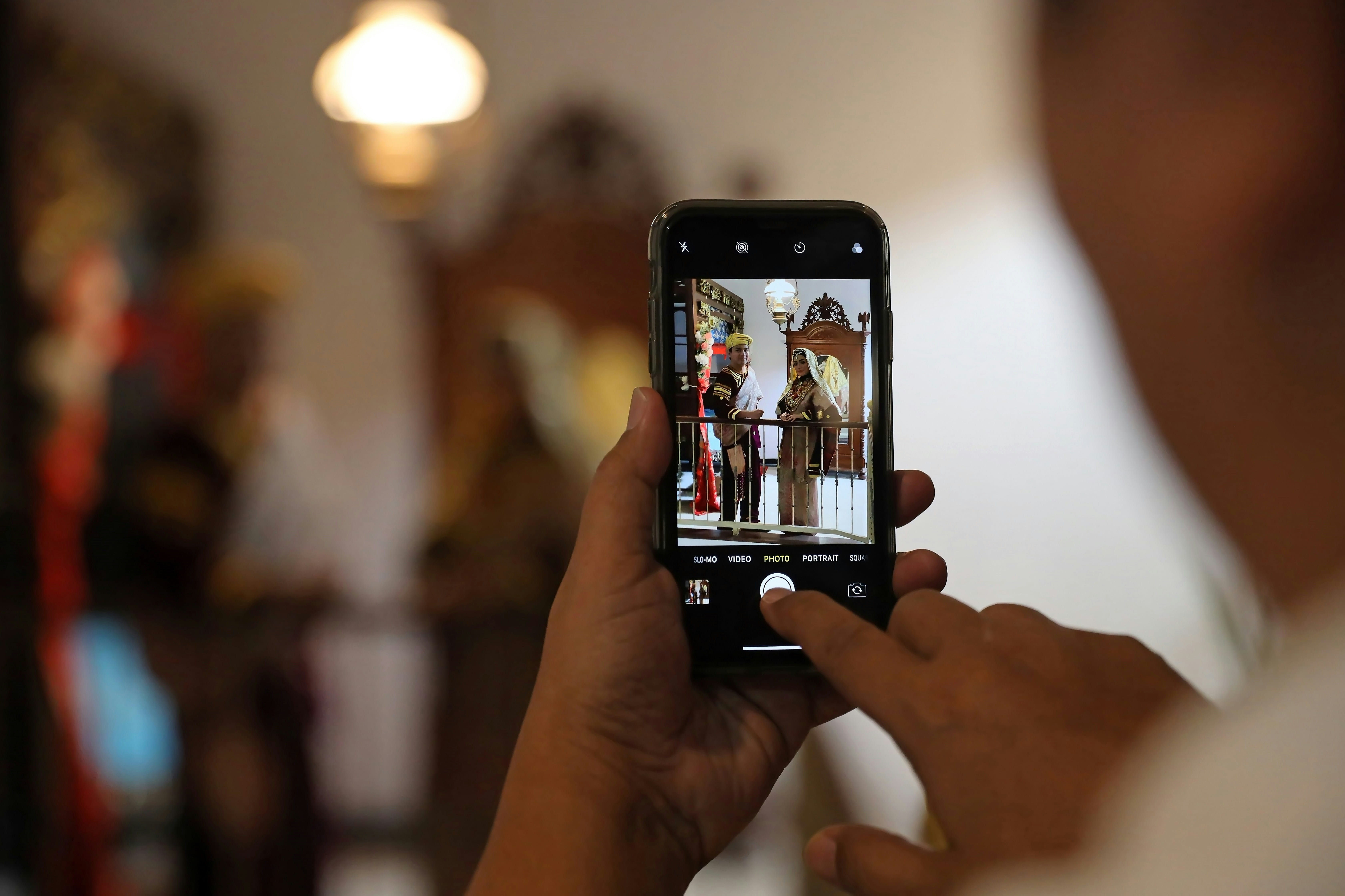 A creator filming a live ceremony on a phone in a crowd