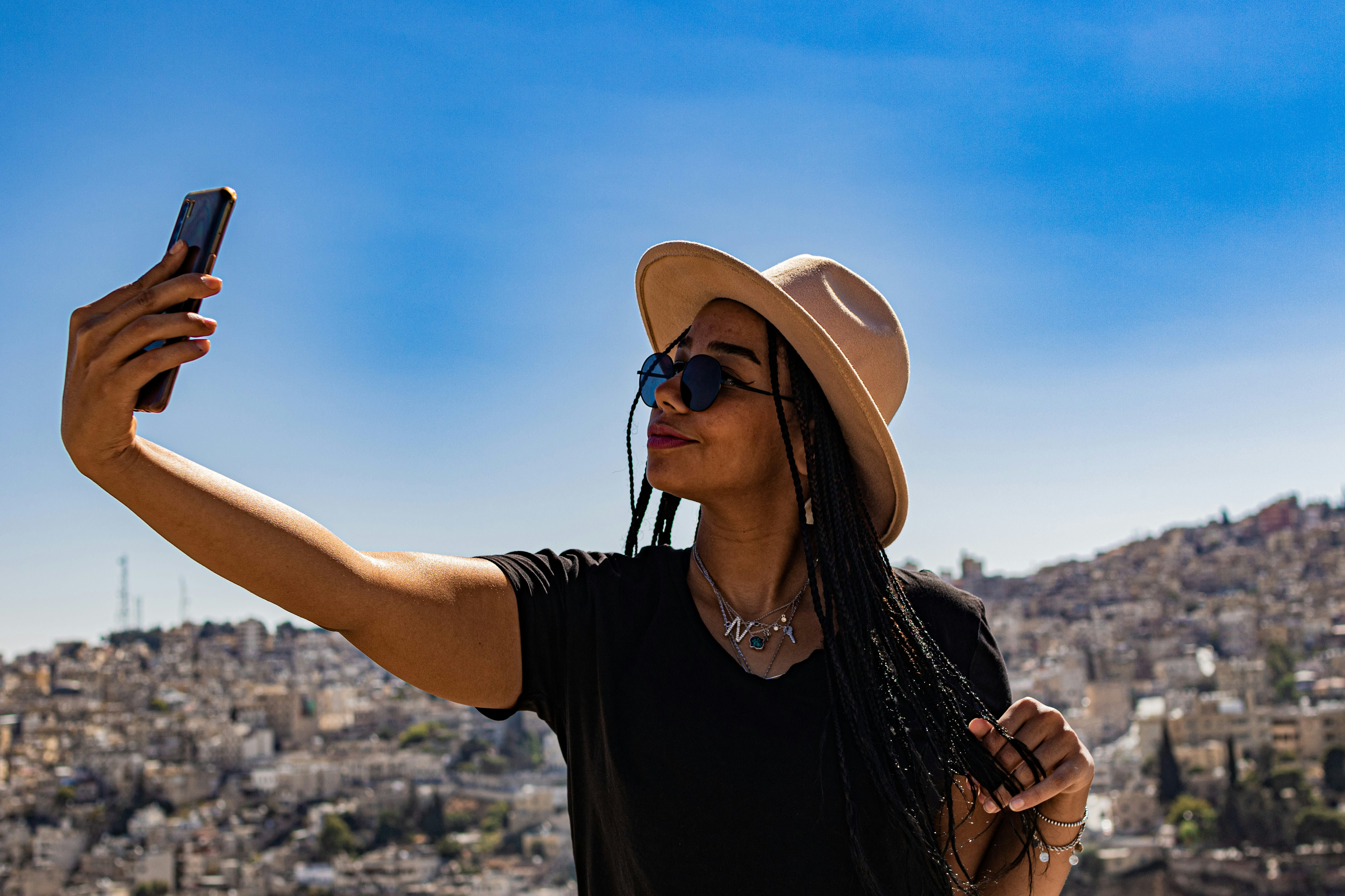A creator capturing a moment on her phone above a city skyline
