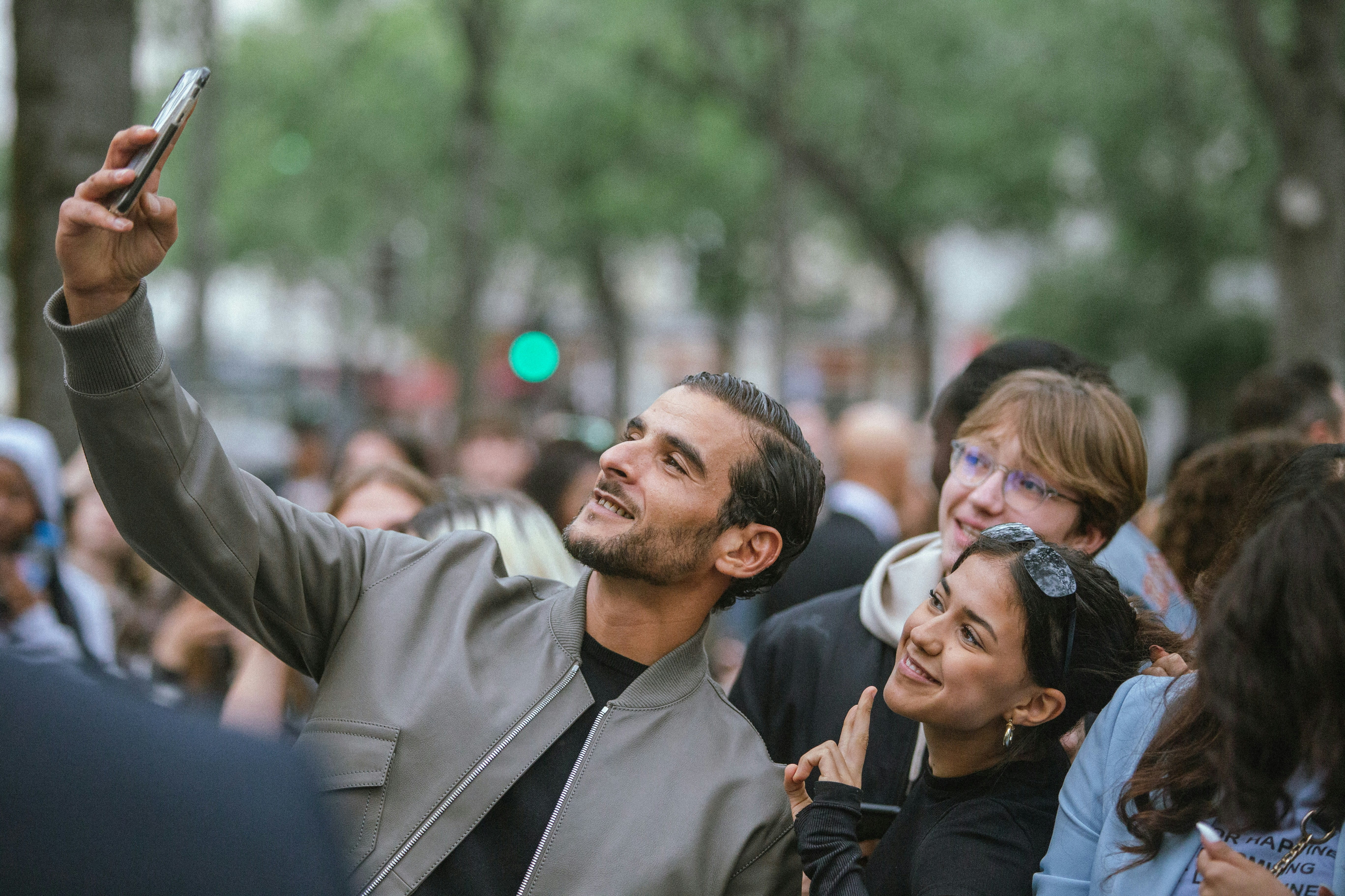 A smiling man taking a selfie in a lively event crowd