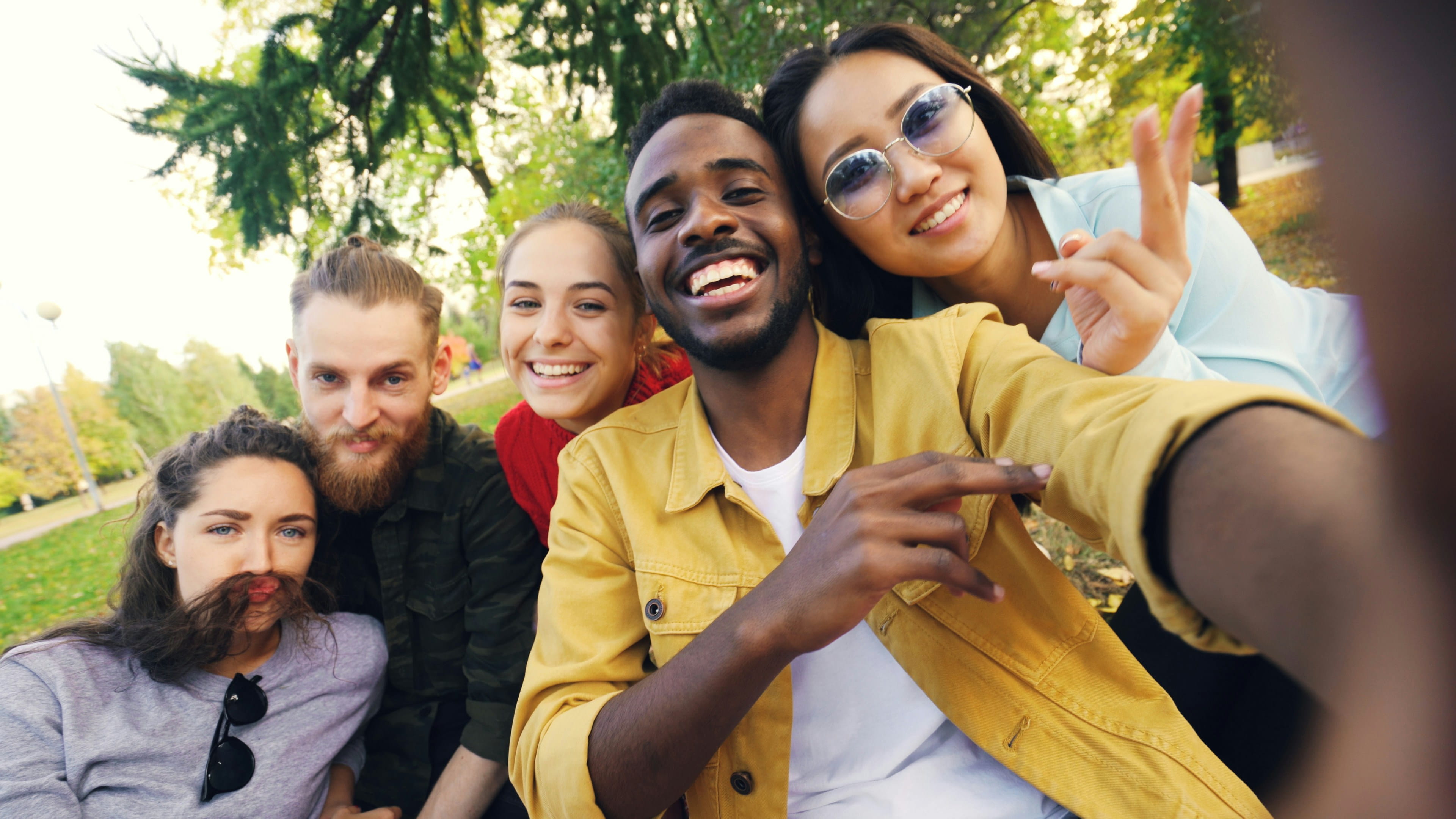 Friends laughing together as they take a group selfie outdoors