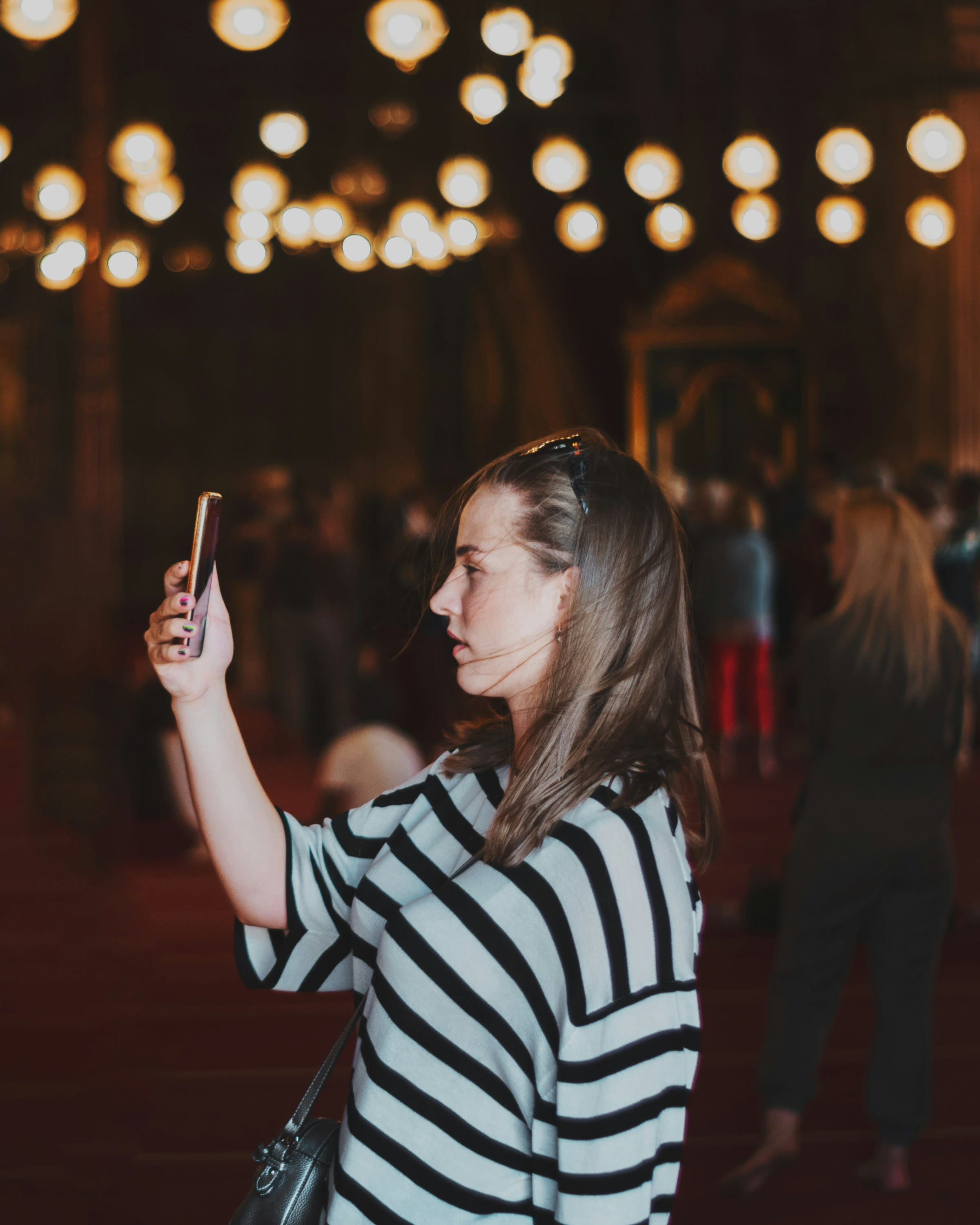 A woman taking a selfie under warm venue lights