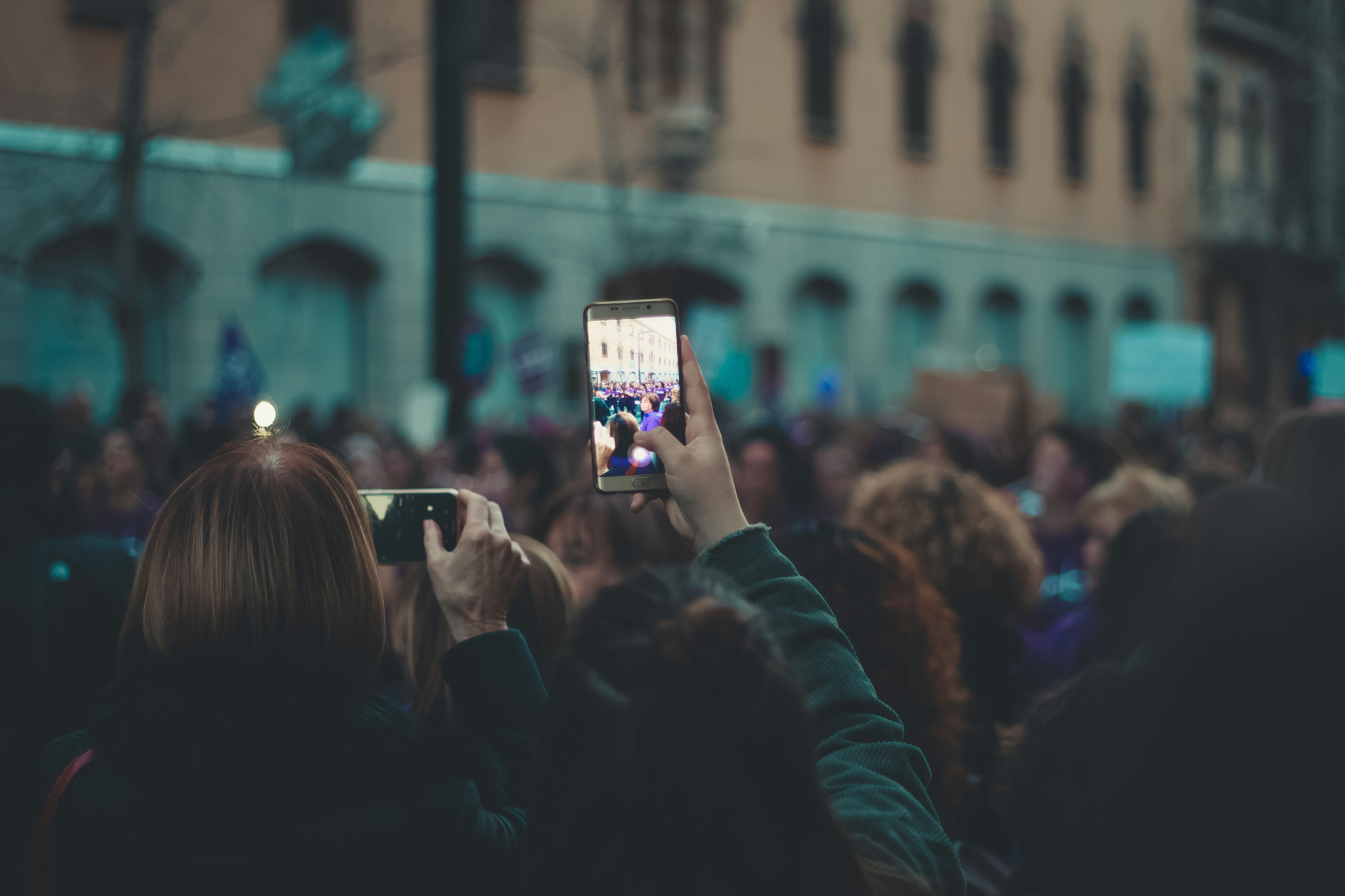 A creator filming a lively night-time event crowd on their phone