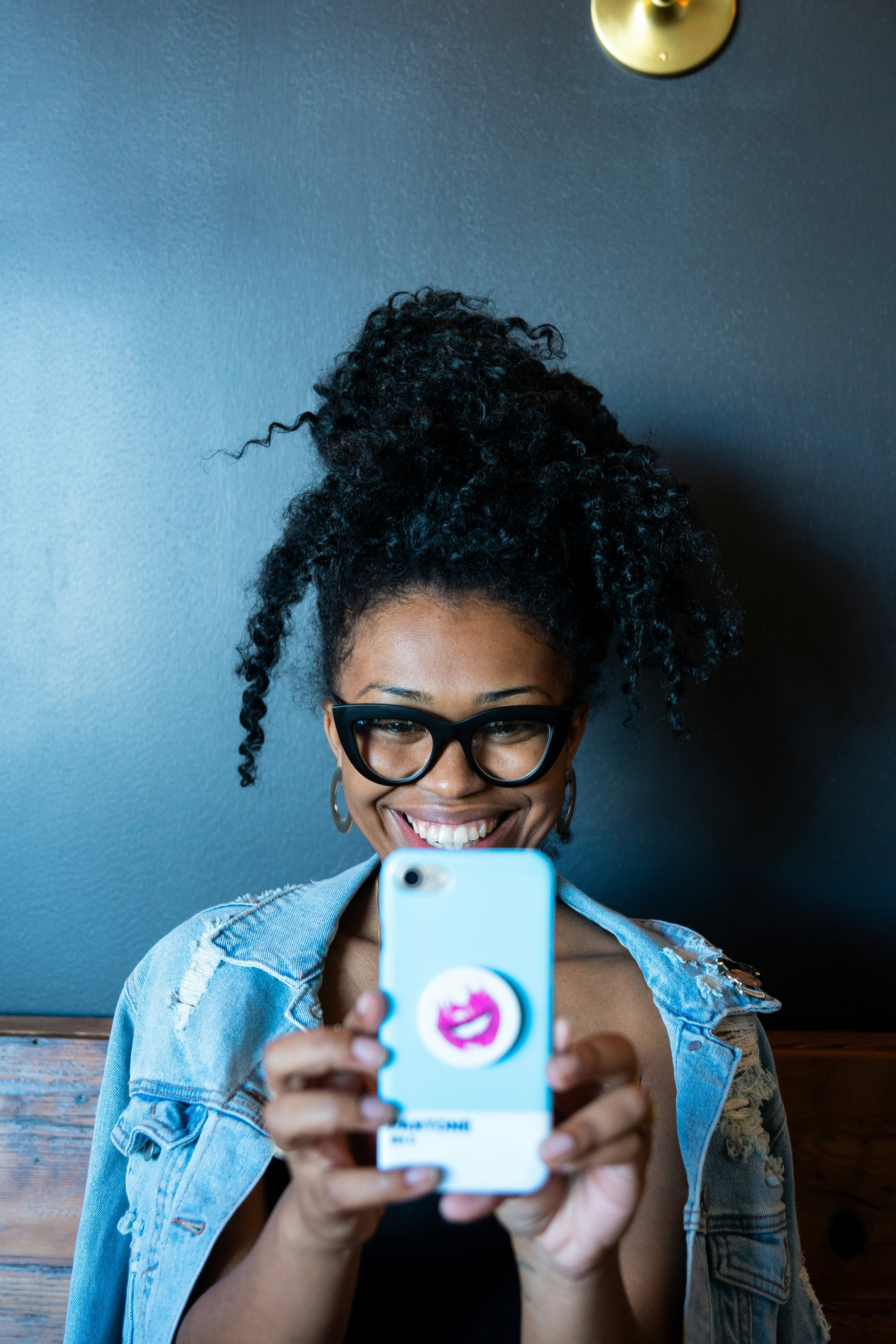 A joyful African woman holding up her phone, ready to create and go live on Vent
