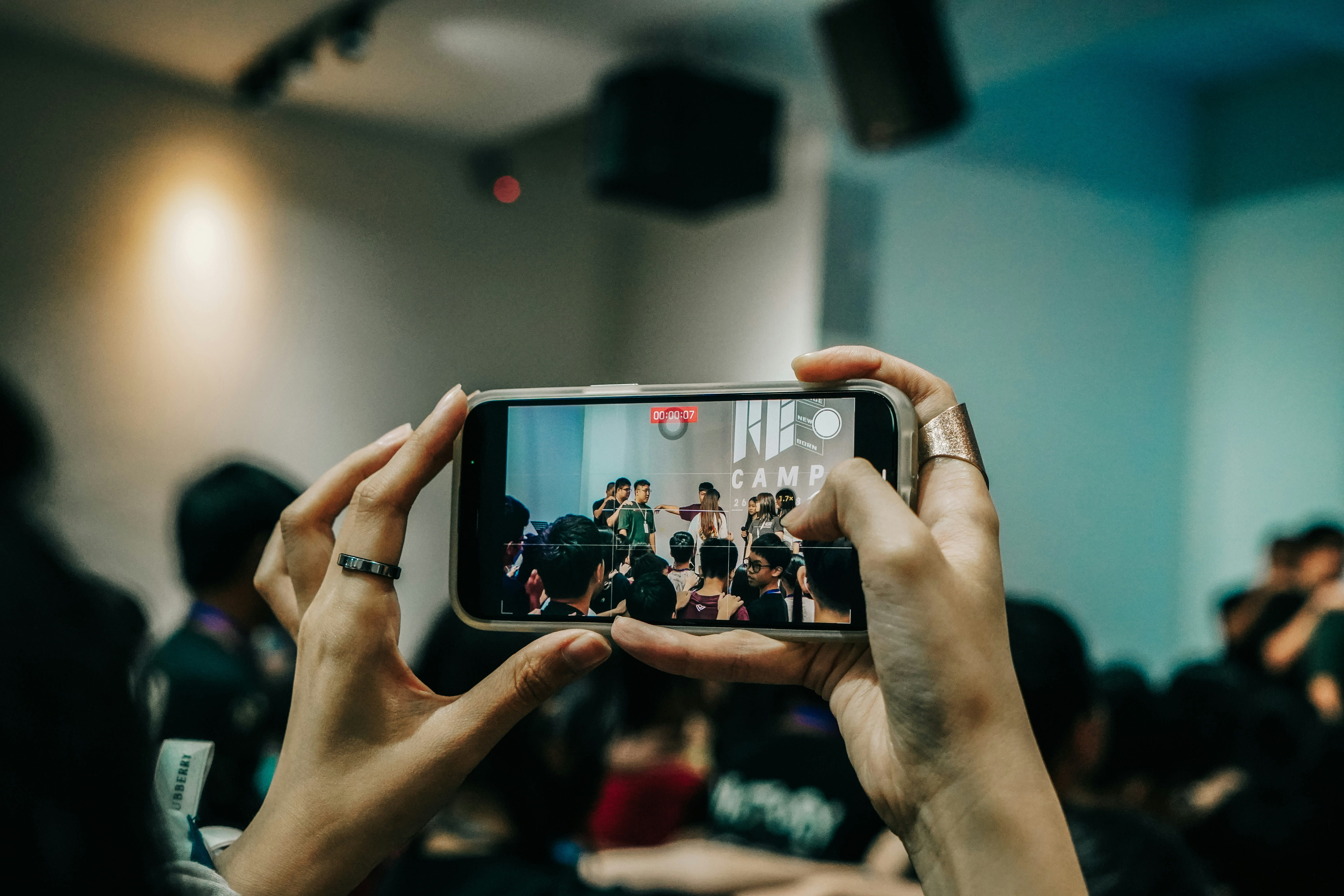 Hands holding up a phone to film a live performance