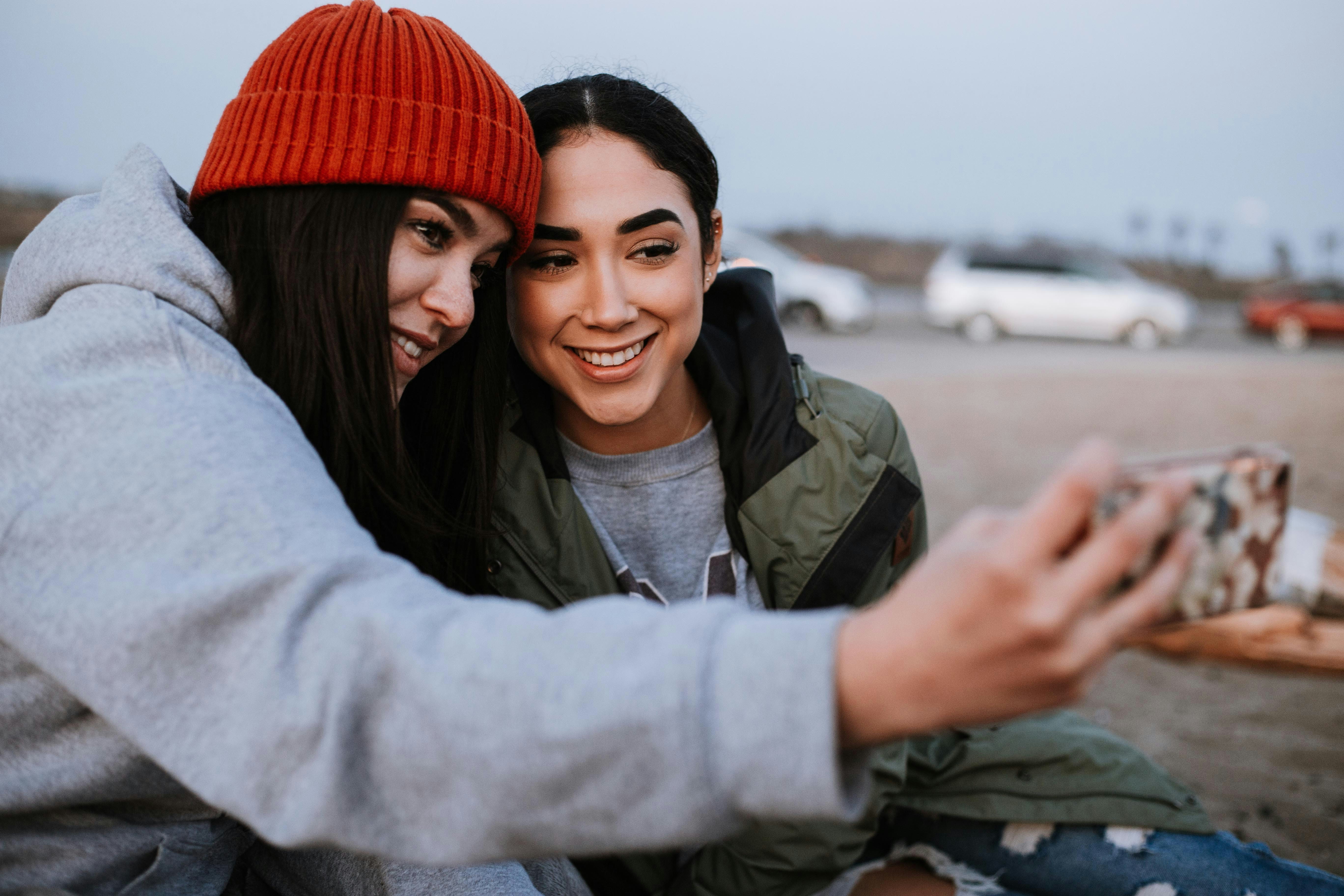 Two friends huddled together taking a selfie, sharing the moment