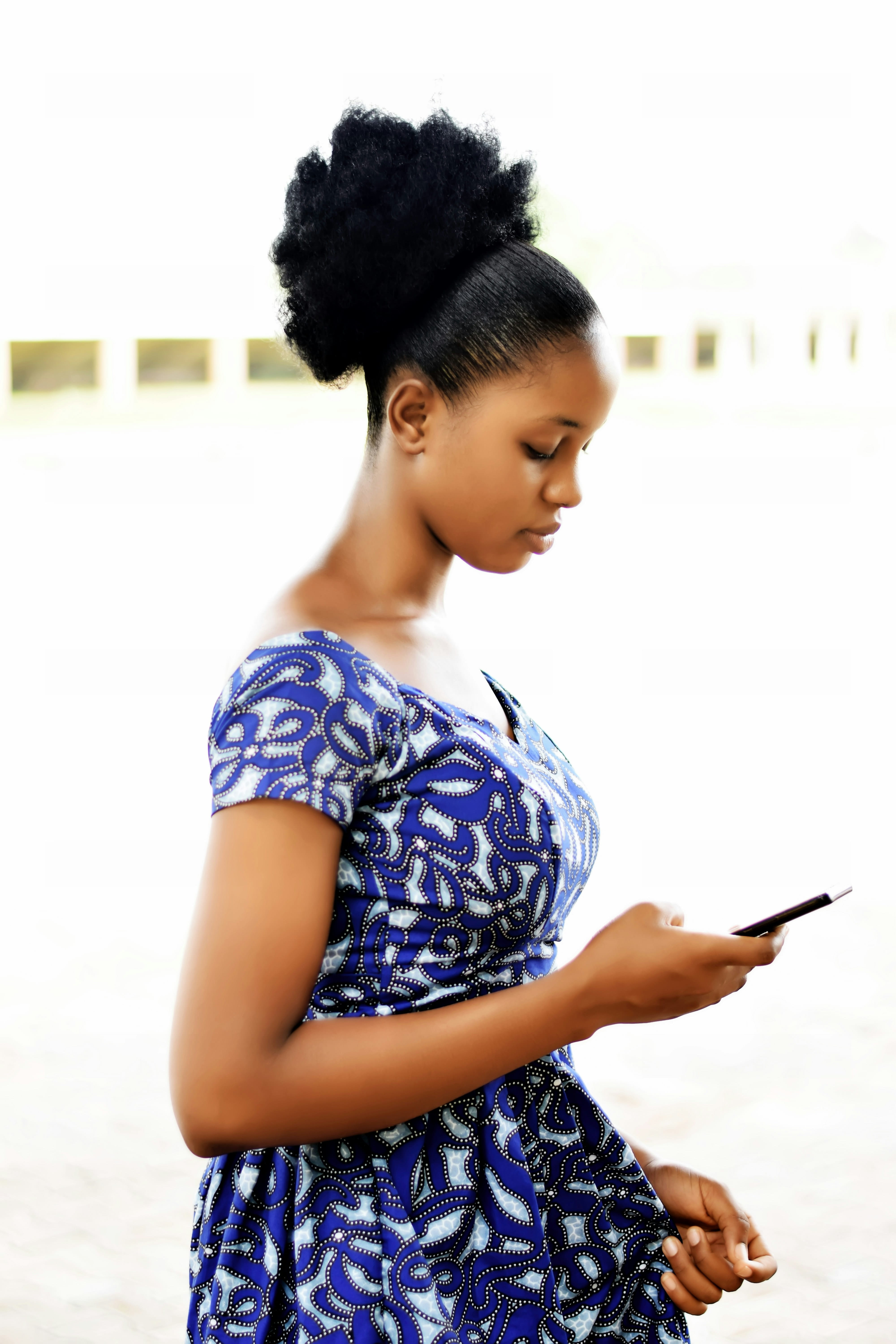 A woman in a bright Ankara dress browsing products on her phone