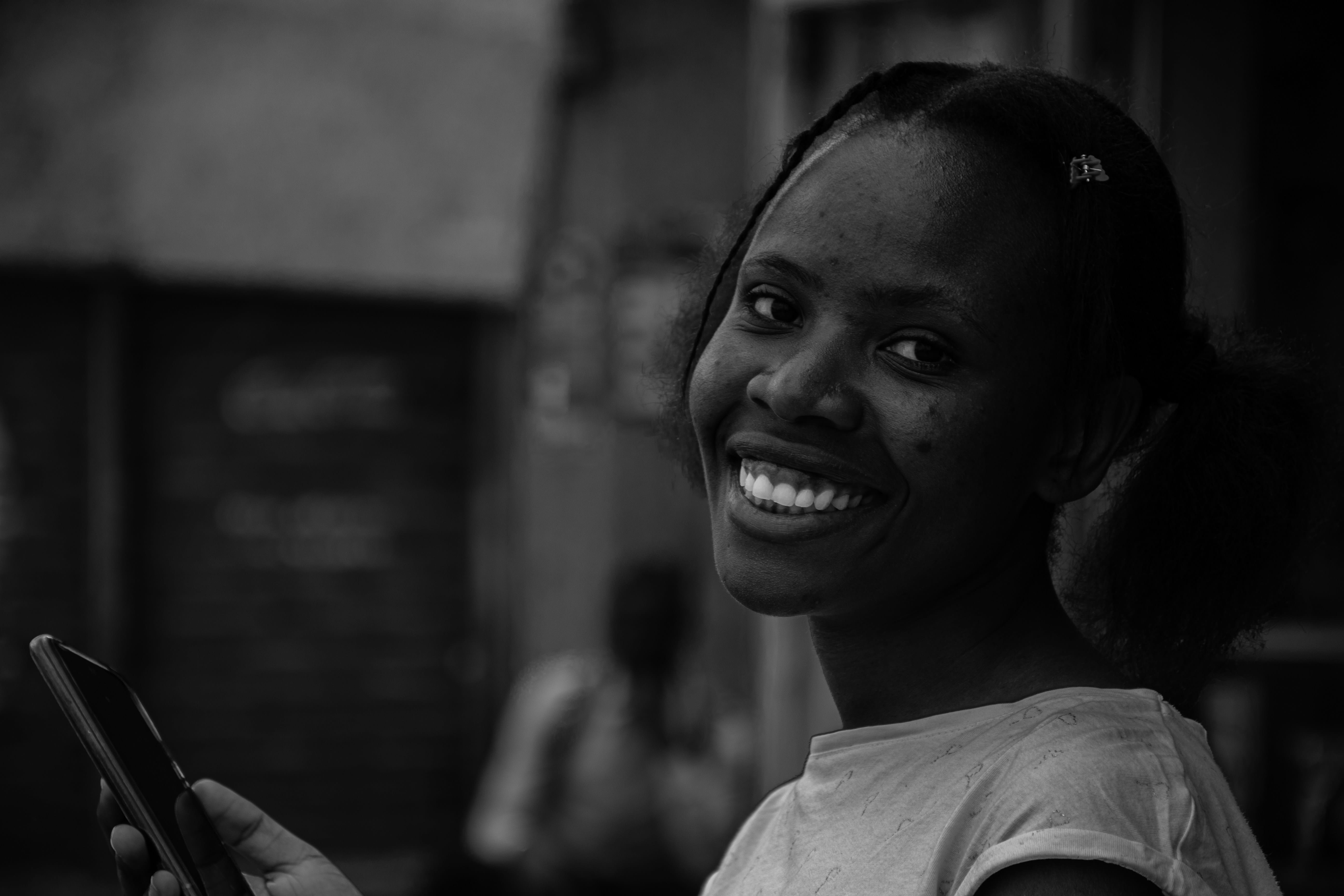 A shopper smiling as she checks her phone on a busy street